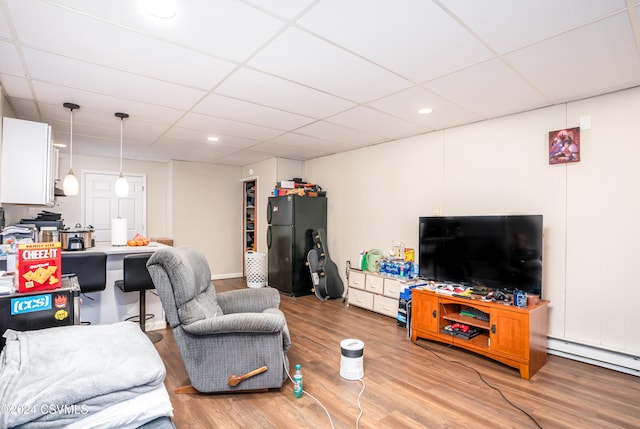 living room with a paneled ceiling, light hardwood / wood-style floors, and a baseboard heating unit