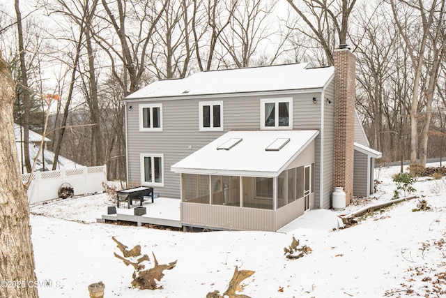 snow covered property with a wooden deck and a sunroom