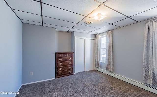 unfurnished bedroom with a paneled ceiling, carpet floors, baseboard heating, and a closet