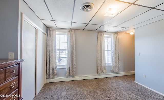 carpeted empty room featuring a drop ceiling and baseboard heating