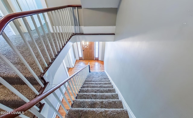 stairs featuring hardwood / wood-style floors and an inviting chandelier