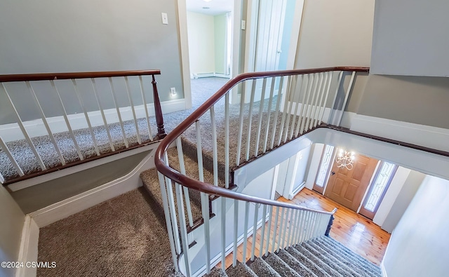 stairs featuring hardwood / wood-style flooring and an inviting chandelier