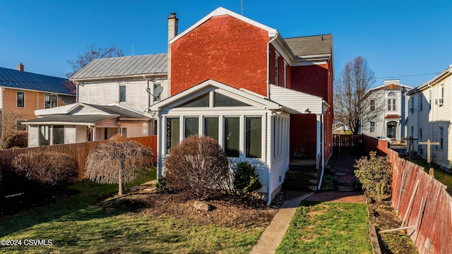 back of property with a yard and a sunroom