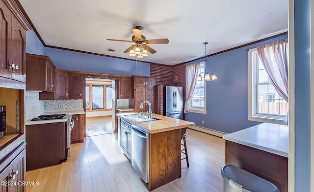 kitchen with a center island with sink, stainless steel appliances, crown molding, and sink