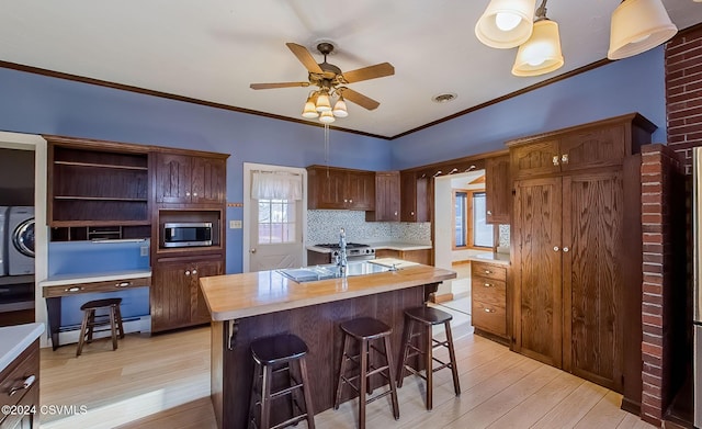 kitchen featuring hanging light fixtures, wooden counters, a baseboard heating unit, light hardwood / wood-style floors, and decorative backsplash