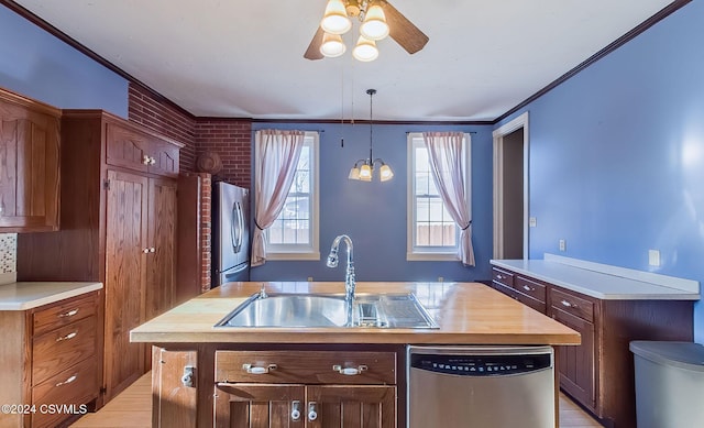 kitchen featuring appliances with stainless steel finishes, crown molding, sink, a center island with sink, and butcher block counters