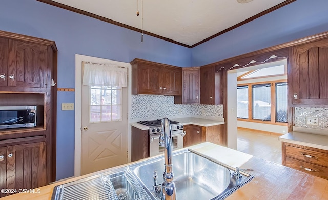 kitchen featuring backsplash, sink, ornamental molding, appliances with stainless steel finishes, and light hardwood / wood-style floors