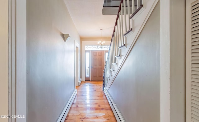 hall with light hardwood / wood-style flooring, a baseboard heating unit, and a notable chandelier