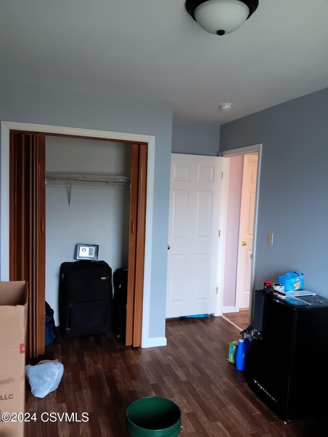 bedroom featuring a closet, refrigerator, and dark wood-type flooring