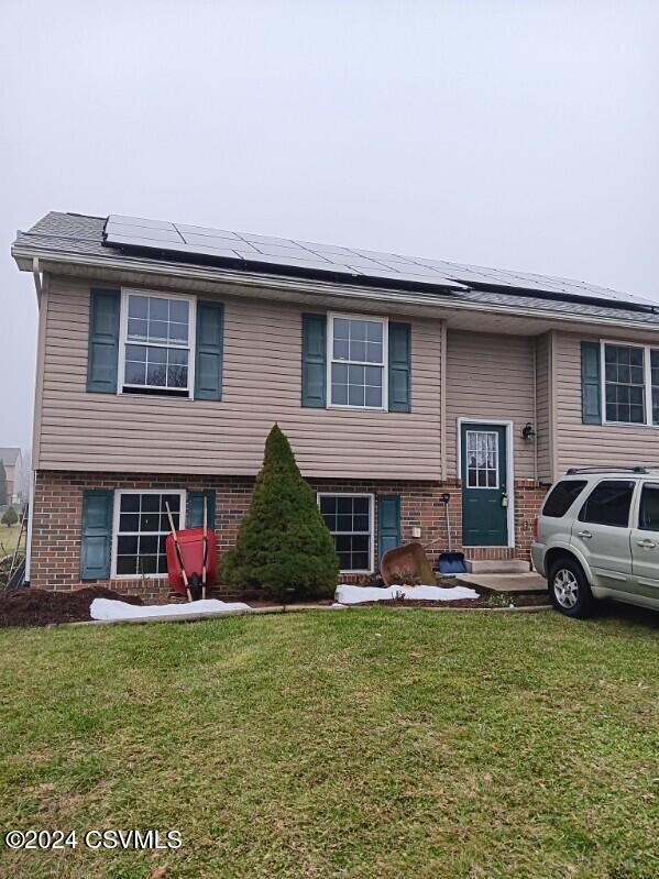 split foyer home with solar panels and a front lawn