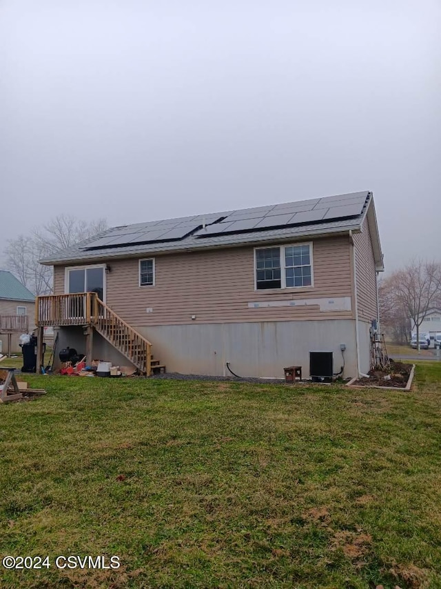 rear view of property featuring solar panels, a yard, and central air condition unit