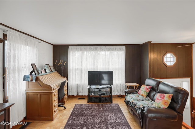 living room featuring light parquet flooring, a wealth of natural light, crown molding, and wood walls