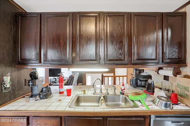 kitchen with tile counters, dishwasher, dark brown cabinetry, and sink