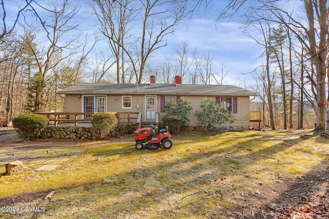 ranch-style home featuring a front lawn and a wooden deck