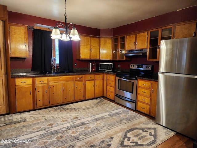 kitchen with stainless steel appliances, sink, pendant lighting, wood-type flooring, and a chandelier