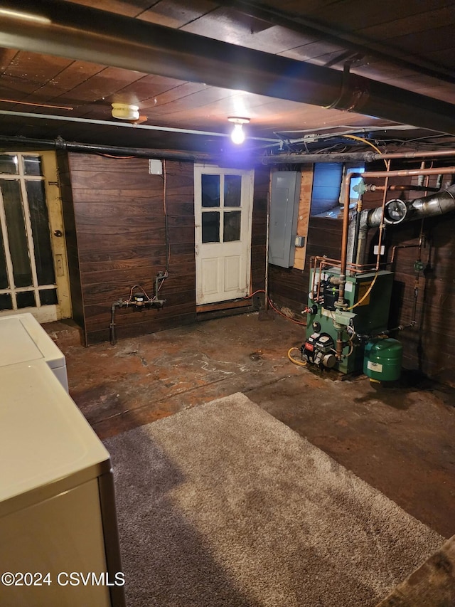 basement featuring washing machine and dryer, electric panel, and wooden walls