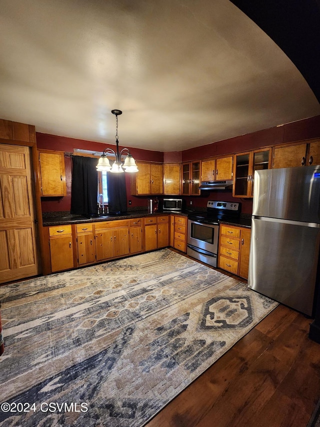 kitchen with appliances with stainless steel finishes, dark hardwood / wood-style flooring, sink, decorative light fixtures, and an inviting chandelier