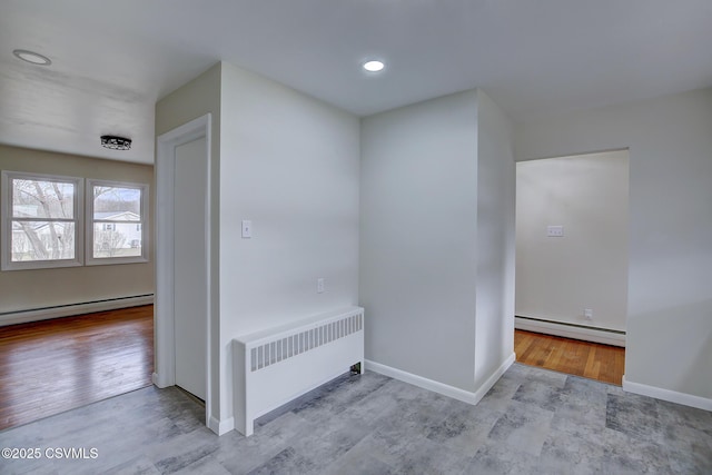 hall with radiator heating unit, light hardwood / wood-style floors, and a baseboard heating unit