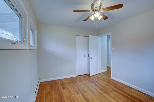 unfurnished room with ceiling fan, a baseboard heating unit, and light wood-type flooring