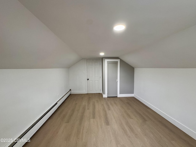 bonus room featuring light wood-type flooring, baseboard heating, and vaulted ceiling