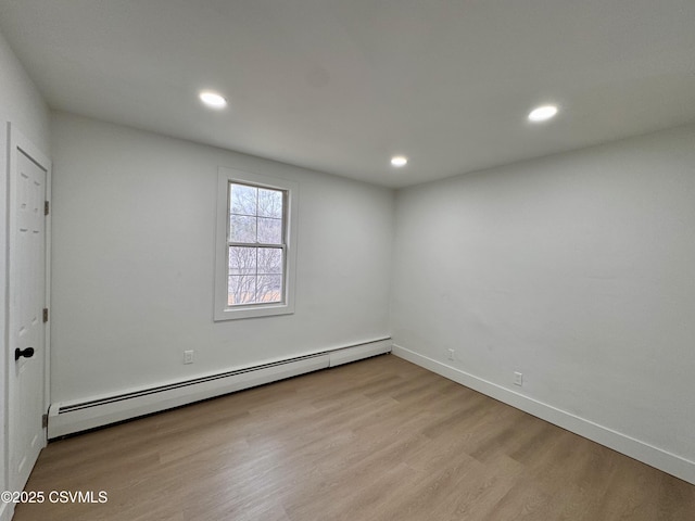 empty room with light wood-type flooring and a baseboard heating unit