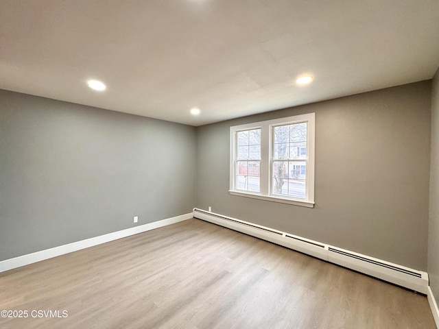 unfurnished room featuring a baseboard radiator and light hardwood / wood-style flooring