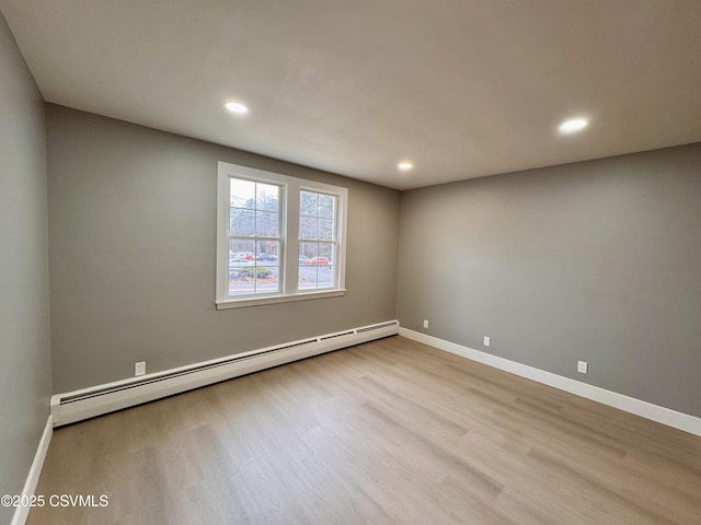 empty room featuring baseboard heating and light hardwood / wood-style floors