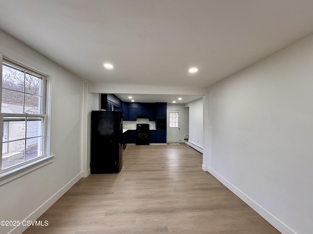 interior space with black refrigerator, wood-type flooring, blue cabinets, and a baseboard radiator