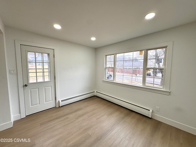 interior space with plenty of natural light, a baseboard radiator, and light hardwood / wood-style flooring