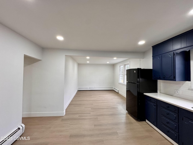 kitchen featuring light wood-type flooring, backsplash, black fridge, and baseboard heating