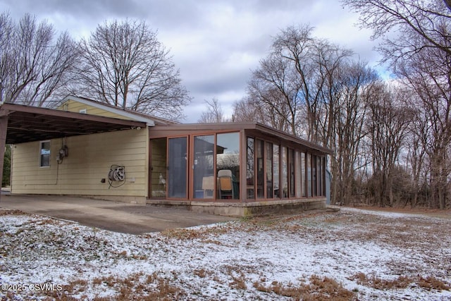 snow covered property with a sunroom and a carport