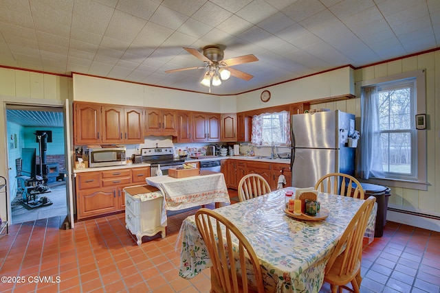 kitchen featuring a wood stove, ceiling fan, crown molding, light tile patterned flooring, and appliances with stainless steel finishes