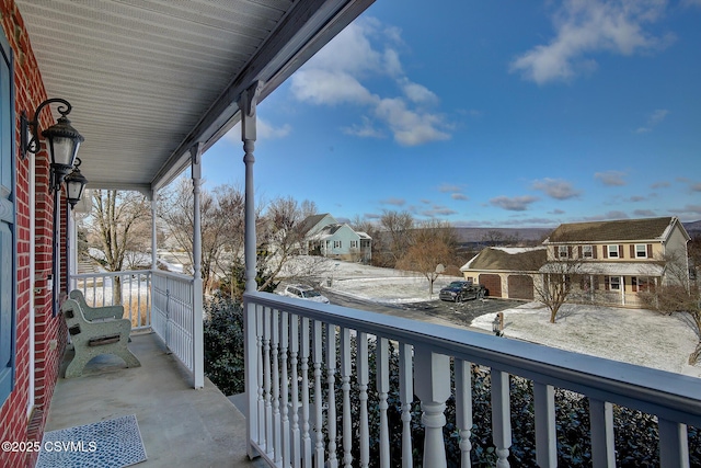 snow covered back of property with a porch