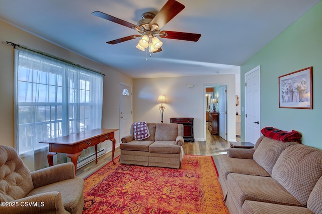 living room with ceiling fan, a baseboard heating unit, and light hardwood / wood-style flooring