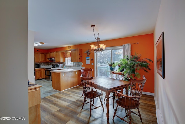 dining room featuring sink, light hardwood / wood-style floors, and a notable chandelier