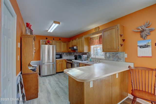 kitchen featuring decorative backsplash, sink, kitchen peninsula, and stainless steel appliances