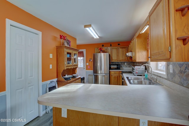 kitchen with kitchen peninsula, stainless steel fridge, backsplash, and sink