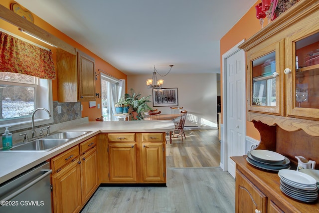 kitchen with sink, tasteful backsplash, stainless steel dishwasher, kitchen peninsula, and a chandelier