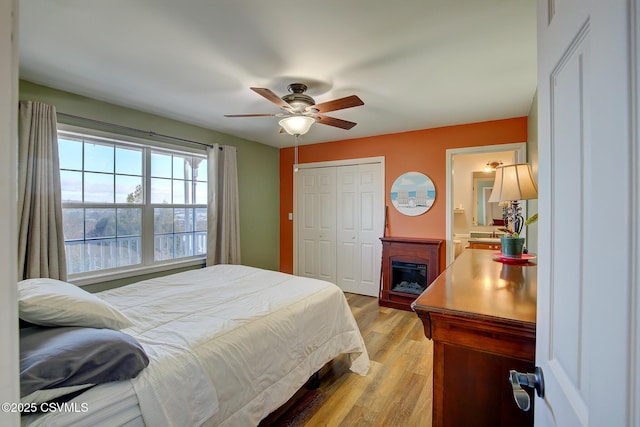 bedroom with light wood-type flooring, ensuite bathroom, and ceiling fan