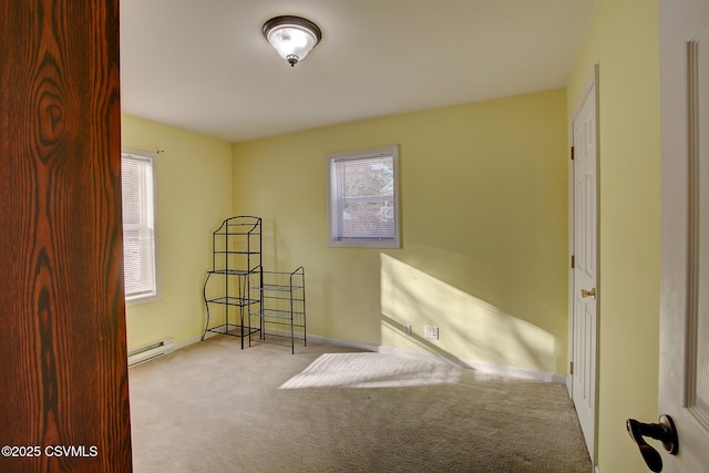 spare room with light carpet, a healthy amount of sunlight, and a baseboard heating unit