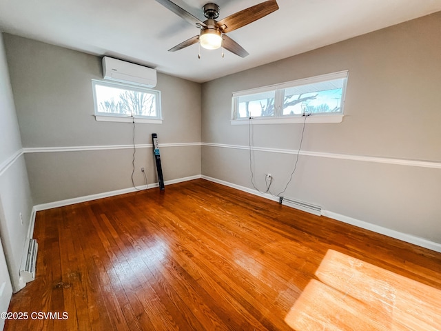 spare room featuring hardwood / wood-style floors, an AC wall unit, and ceiling fan