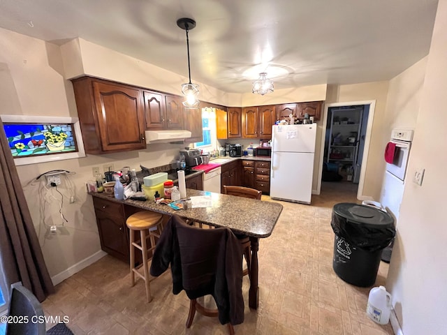 kitchen featuring kitchen peninsula, a breakfast bar, hanging light fixtures, and white appliances