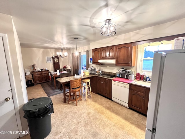 kitchen featuring pendant lighting, white appliances, and a chandelier