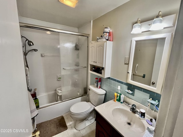 full bathroom featuring shower / bath combination with glass door, vanity, toilet, and tile walls