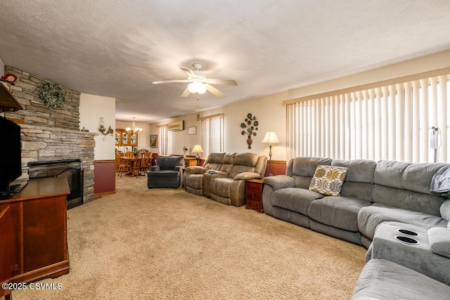 living room with a textured ceiling, ceiling fan, carpet floors, and a stone fireplace