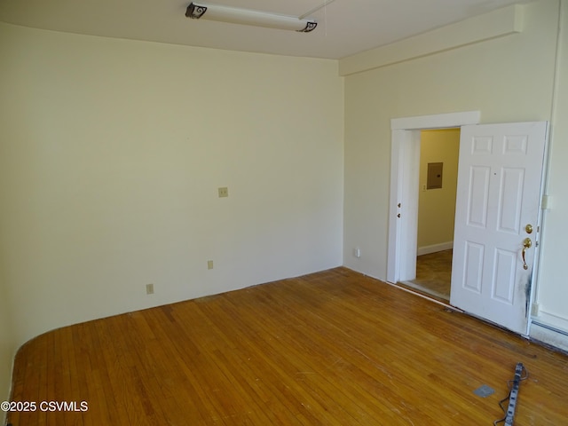 empty room with electric panel and hardwood / wood-style floors