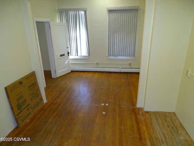 unfurnished room featuring a baseboard heating unit and hardwood / wood-style flooring