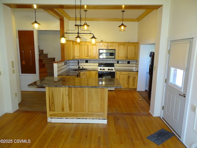 kitchen featuring gas stove, sink, backsplash, pendant lighting, and light wood-type flooring