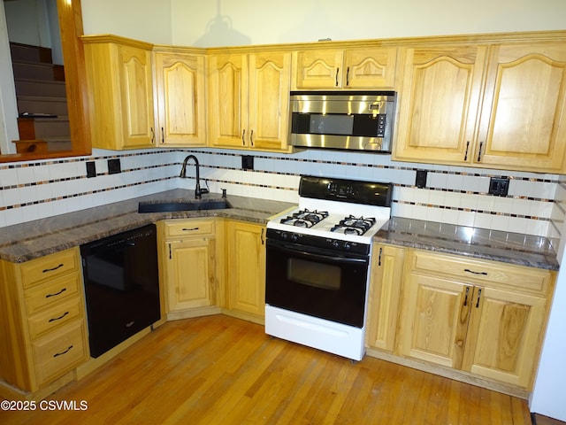 kitchen with dishwasher, sink, range with gas cooktop, dark stone counters, and decorative backsplash