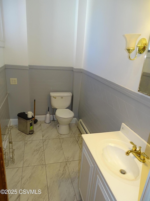 bathroom with vanity, toilet, tile walls, and a baseboard heating unit